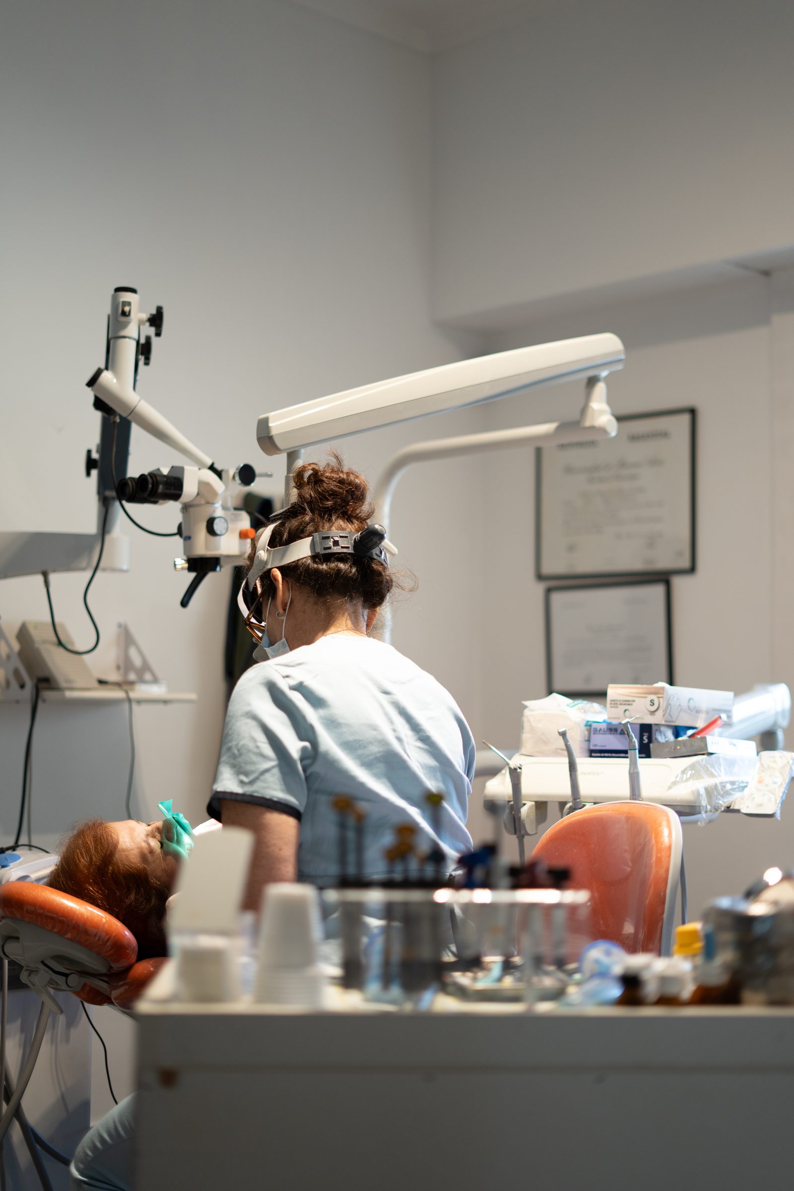 Odontóloga atendiendo a una paciente con microscopio